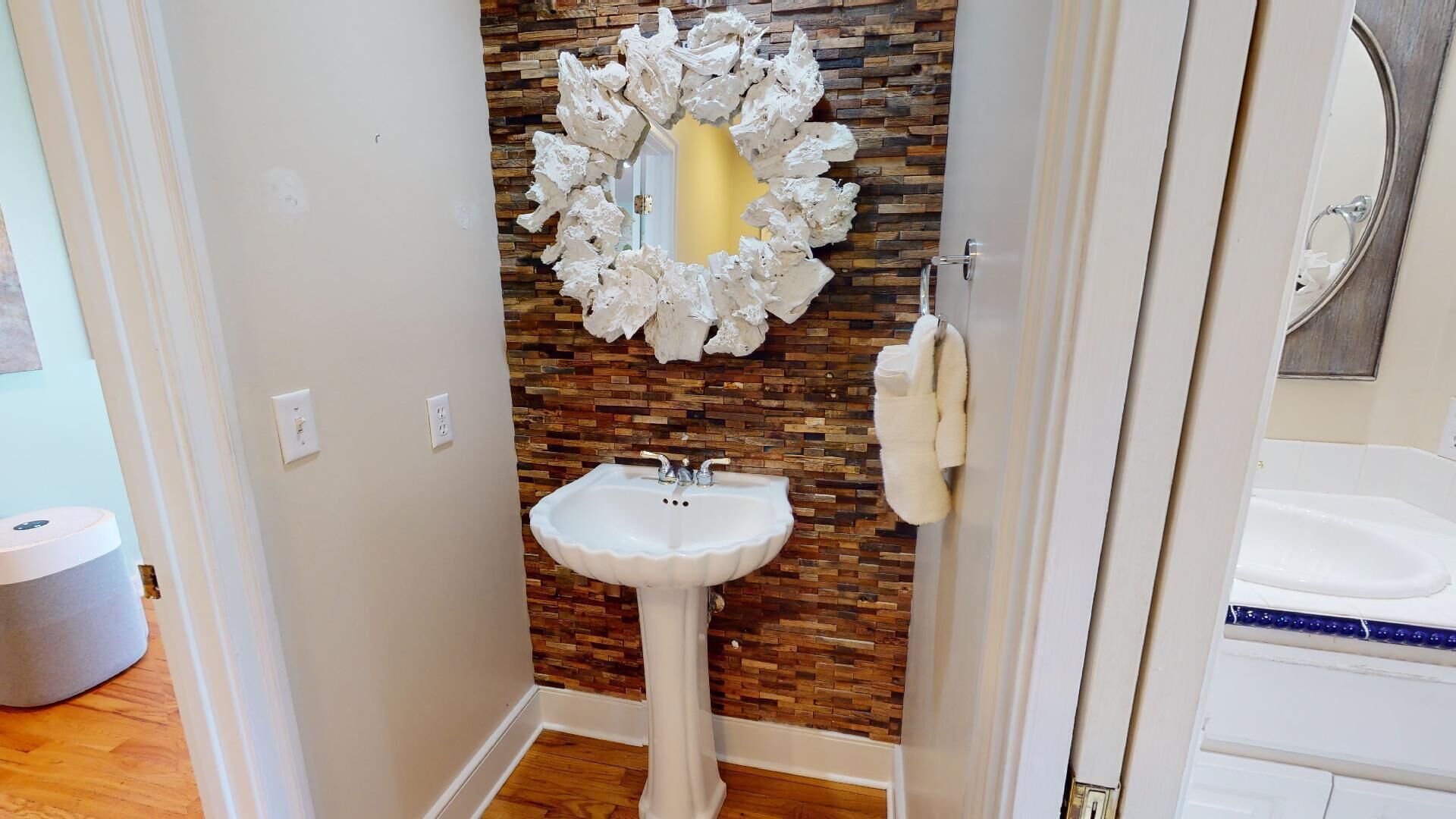 A bathroom with a white sink, a mirror with a white frame, and a wooden wall.