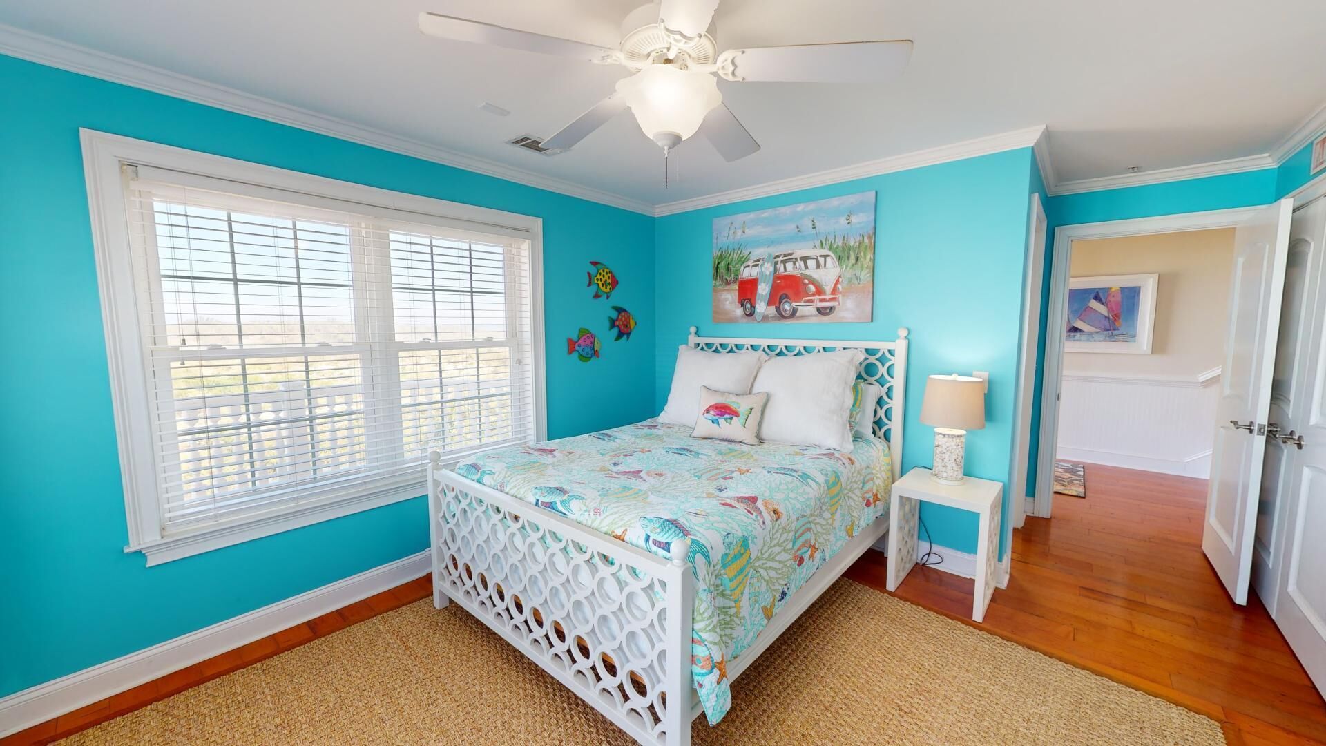 A bedroom with a bed, a nightstand, a ceiling fan, a window with blinds, and a door.