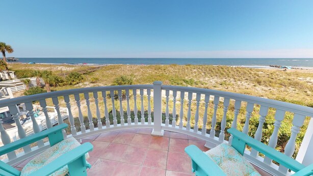 A balcony with a white railing, turquoise chairs, and a view of the beach and ocean. - 1801-B Strand Avenue by Tybee Vacation Rentals (Tybee Island)