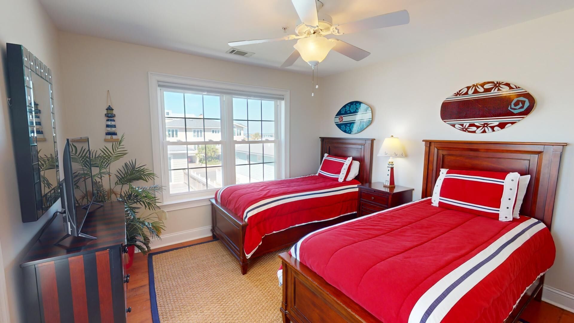 A hotel room with two beds, a ceiling fan, a large window, and a view of the city.