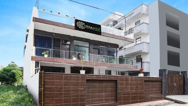 A modern multi-story building with a sign for "URBAN Nest." - Urban Nest Rooms & Rooftop Restaurant (Noida)