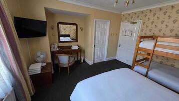 Una habitación de hotel con cama, escritorio, silla, televisor y armario.