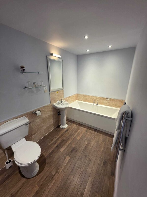 A modern bathroom with a toilet, pedestal sink, and freestanding bathtub.