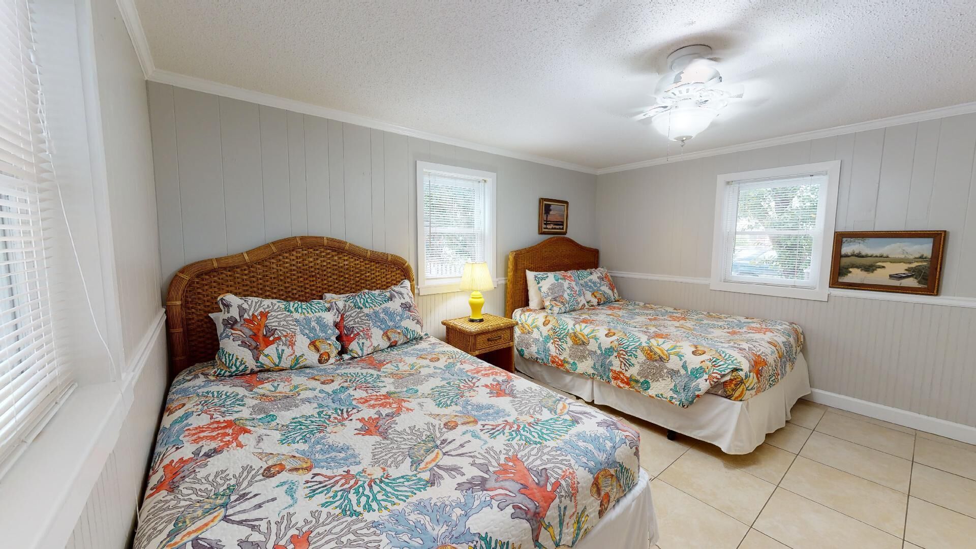 A bedroom with two single beds, a ceiling fan, and a window with blinds.