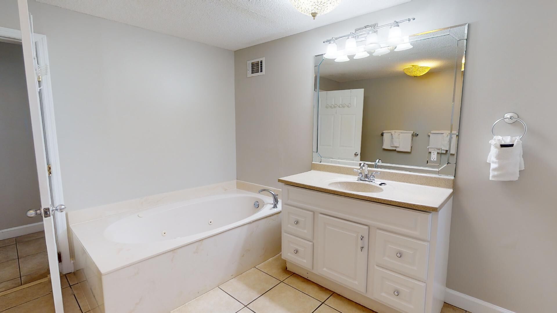 A bathroom with a bathtub, a sink, and a large mirror.