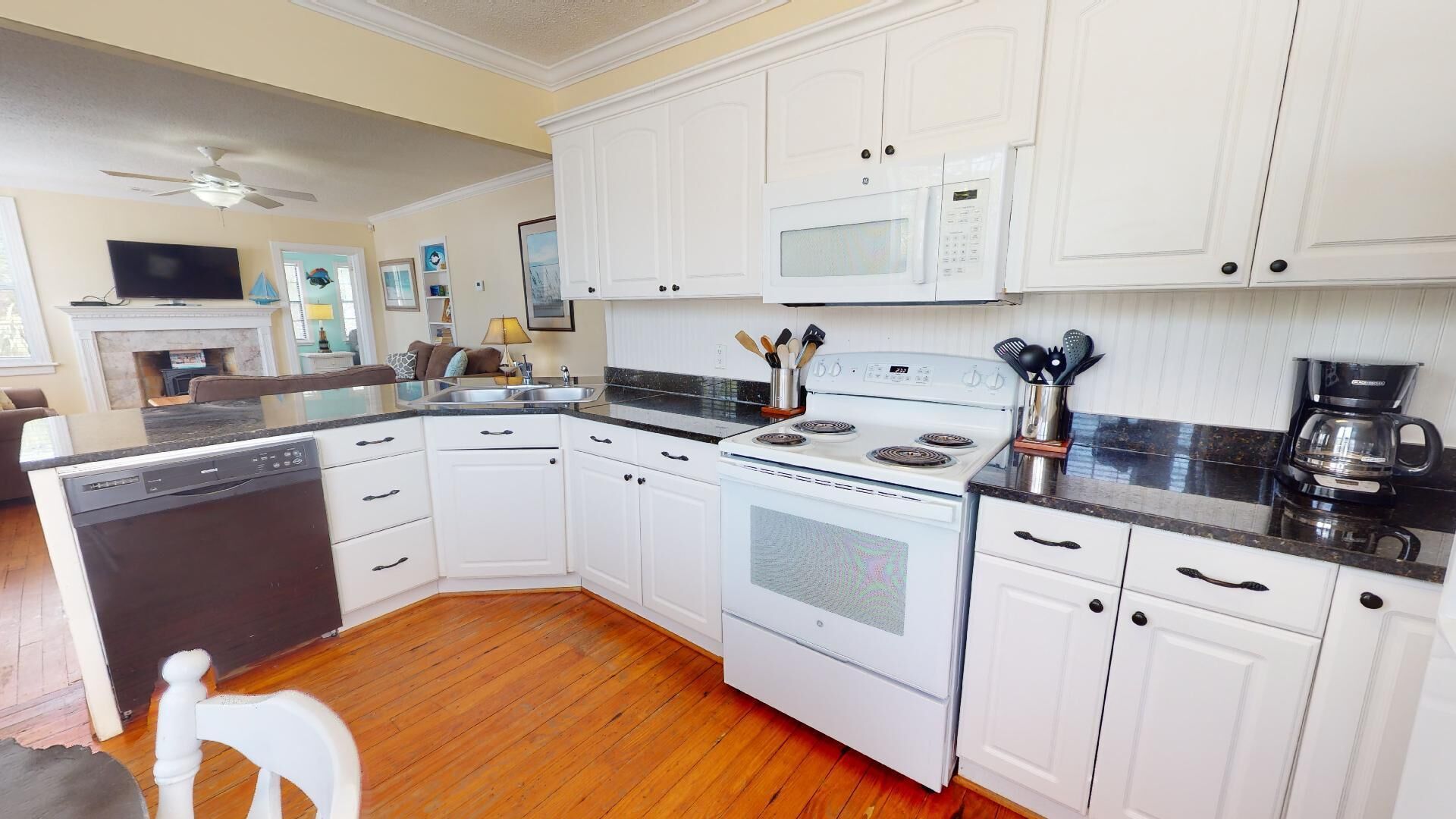 A kitchen with white cabinets, a stove, a microwave, and a dishwasher.