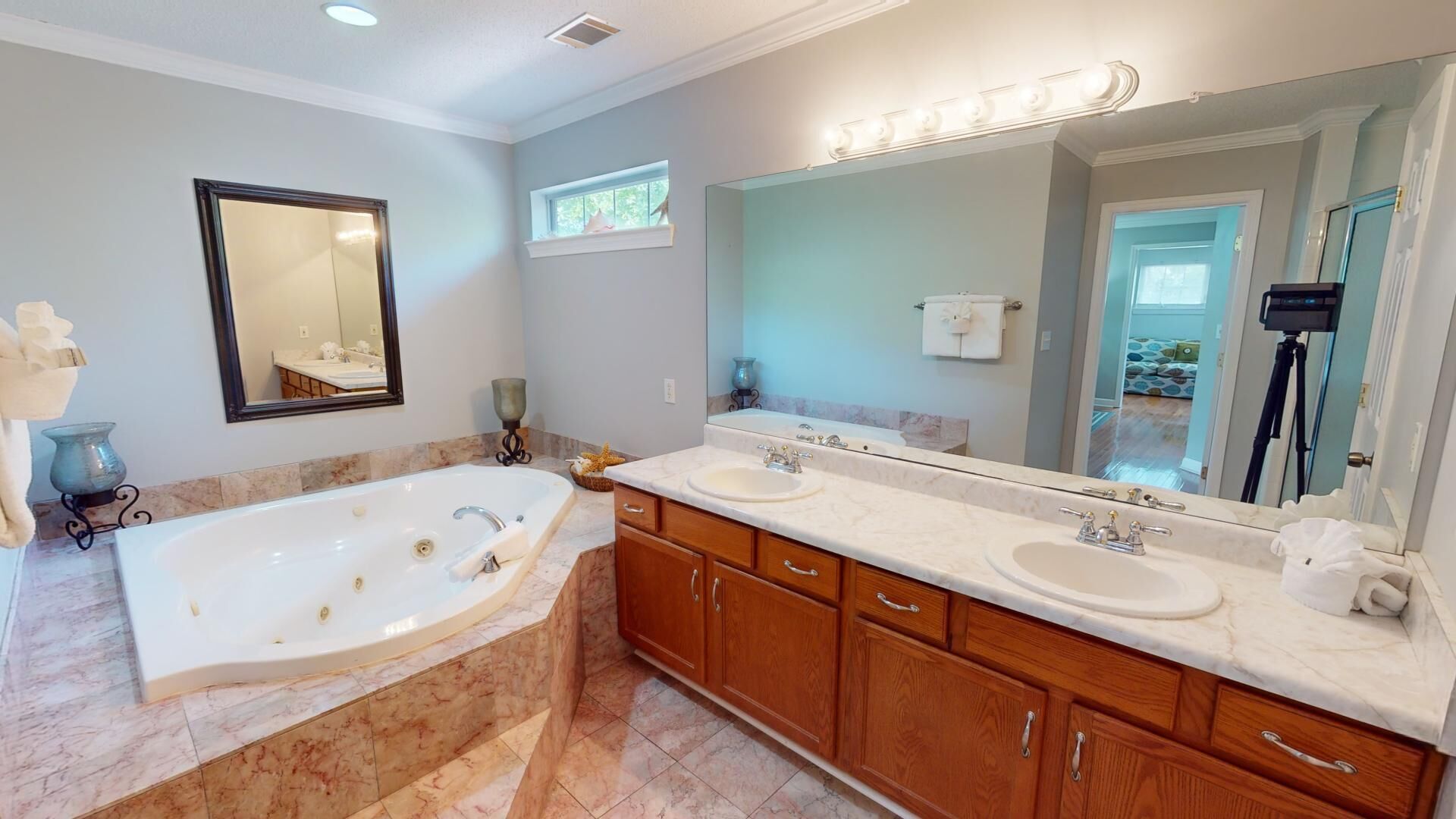 A bathroom with a large freestanding bathtub, two sinks, wooden cabinets, and a large mirror.
