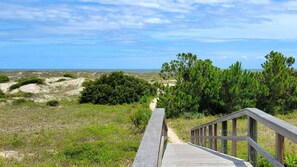 A wooden boardwalk leading to a beach with dunes and pine trees. - 3 10th Place by Tybee Vacation Rentals (Tybee Island)