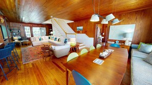 Un vaste espace de vie doté d’un plancher en bois, d’une grande table à manger en bois et d’un escalier menant à l’étage supérieur.