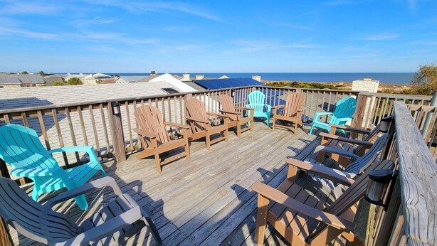 A wooden deck with several Adirondack chairs and a view of the ocean. - 4-B 12th Street by Tybee Vacation Rentals (Tybee Island)
