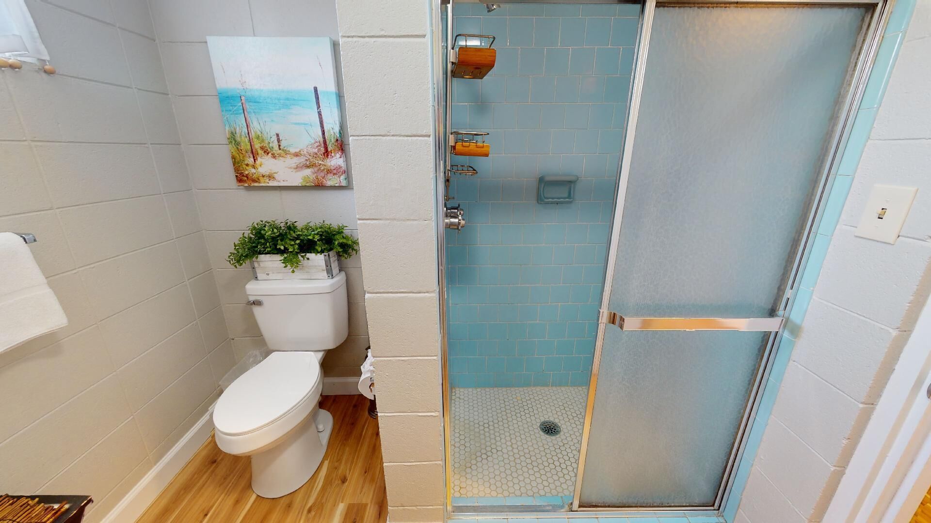 Une salle de bain avec des toilettes, une douche dotée d’une porte en verre et une petite fenêtre.