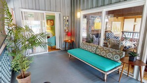 A cozy room with a teal sofa, a wicker plant, and a small table with a lamp.