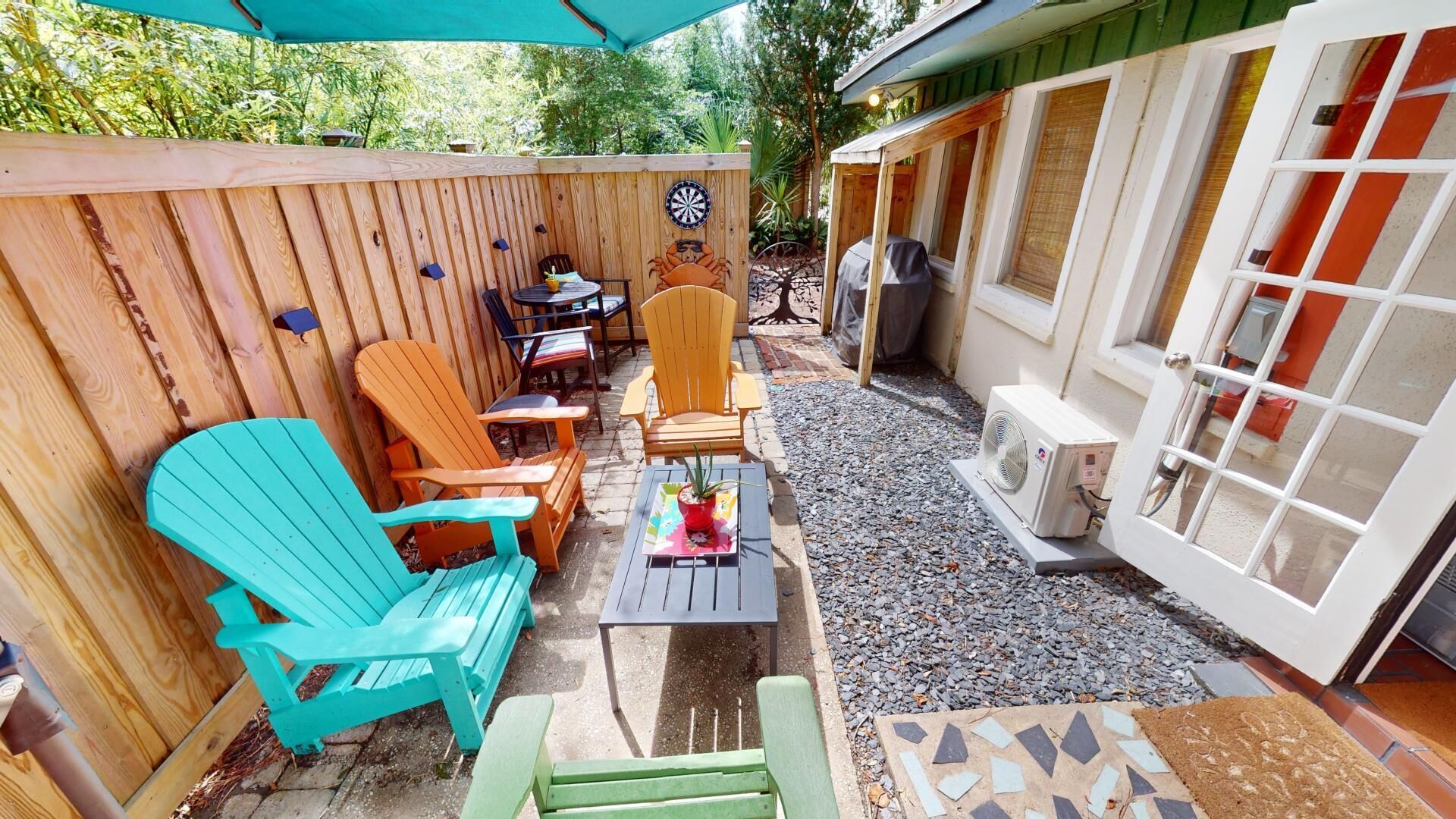 A patio with wooden furniture, a dartboard, and a grill area.