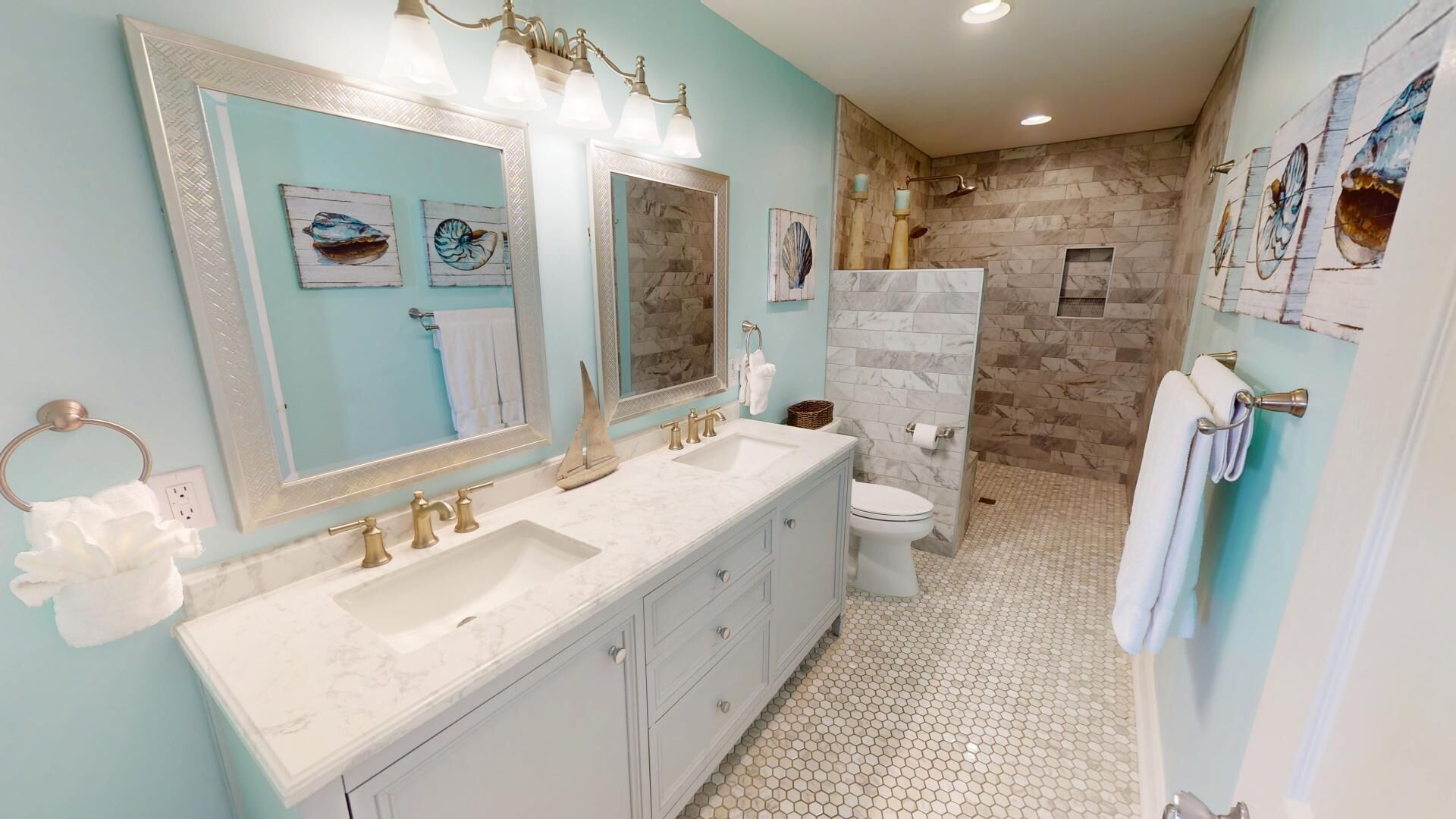 A bathroom with a large vanity, two sinks, a toilet, and a shower area.