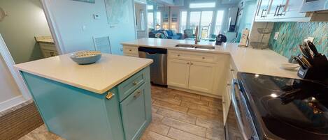 A kitchen with a central island, a dishwasher, and a stove.