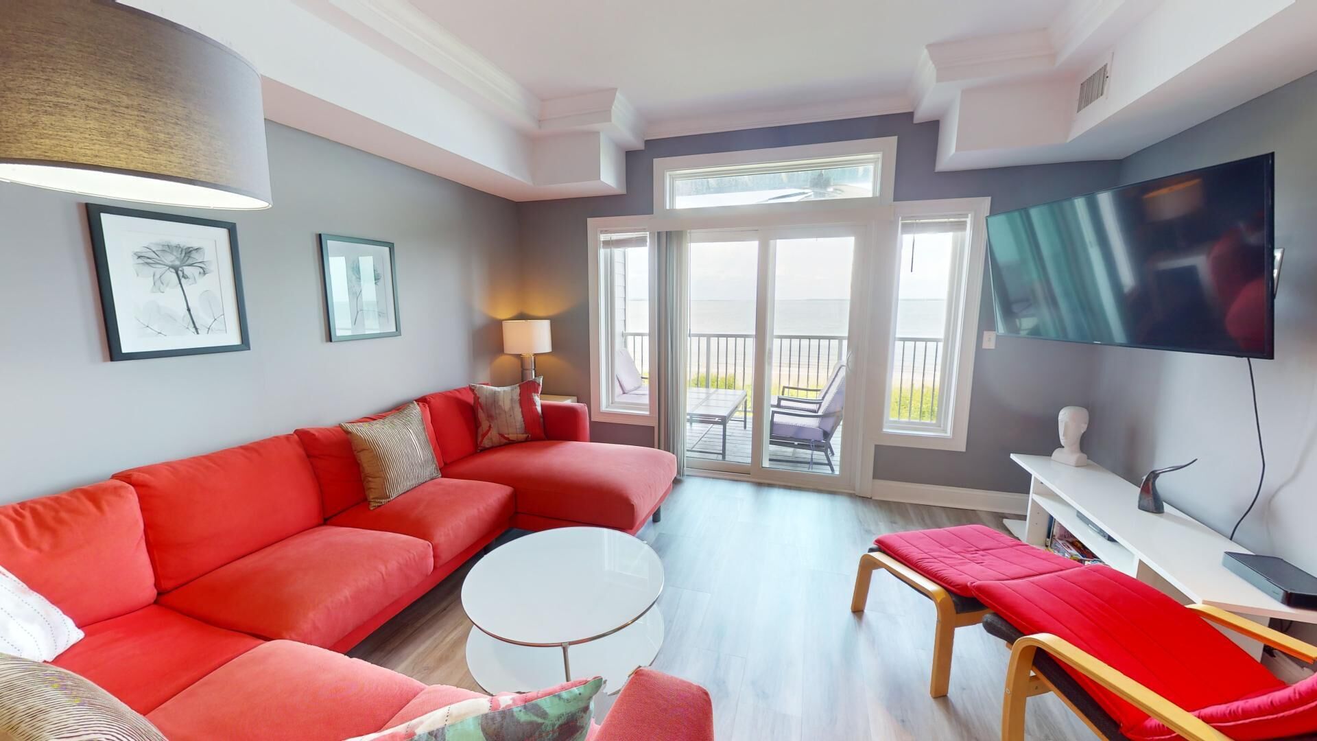 A modern living room with a red sofa, a round coffee table, and a TV mounted on the wall.