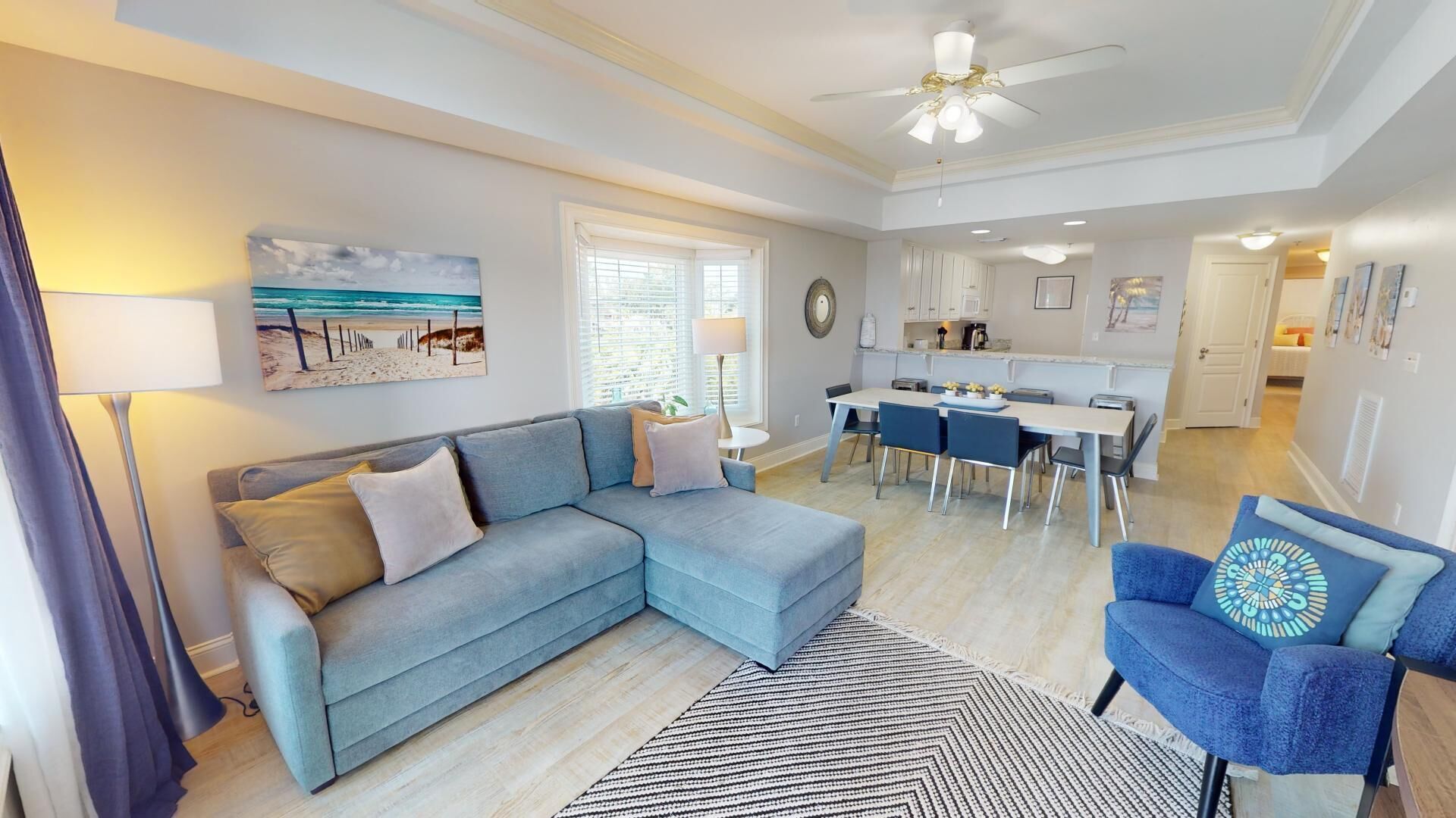 A modern living room with a sofa, a dining area, and a kitchen in the background.