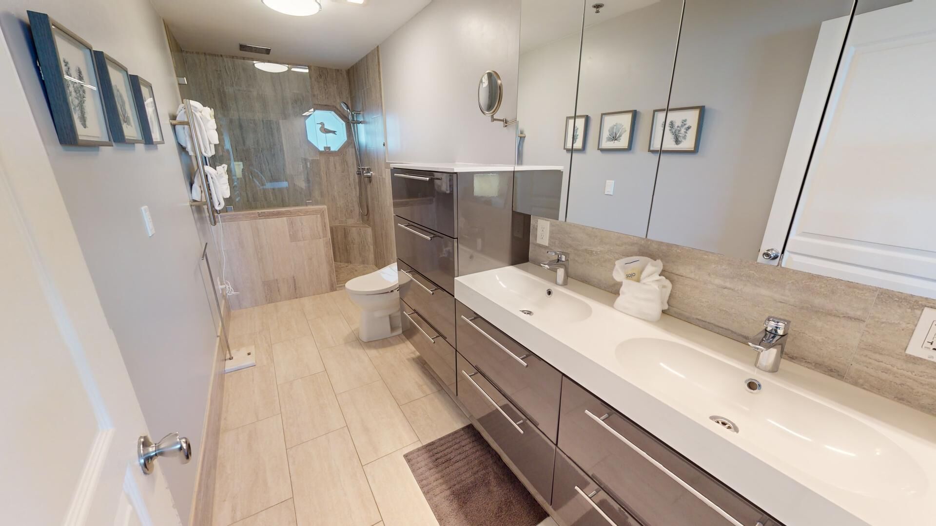 A modern bathroom with a shower, toilet, and a vanity with a large mirror.
