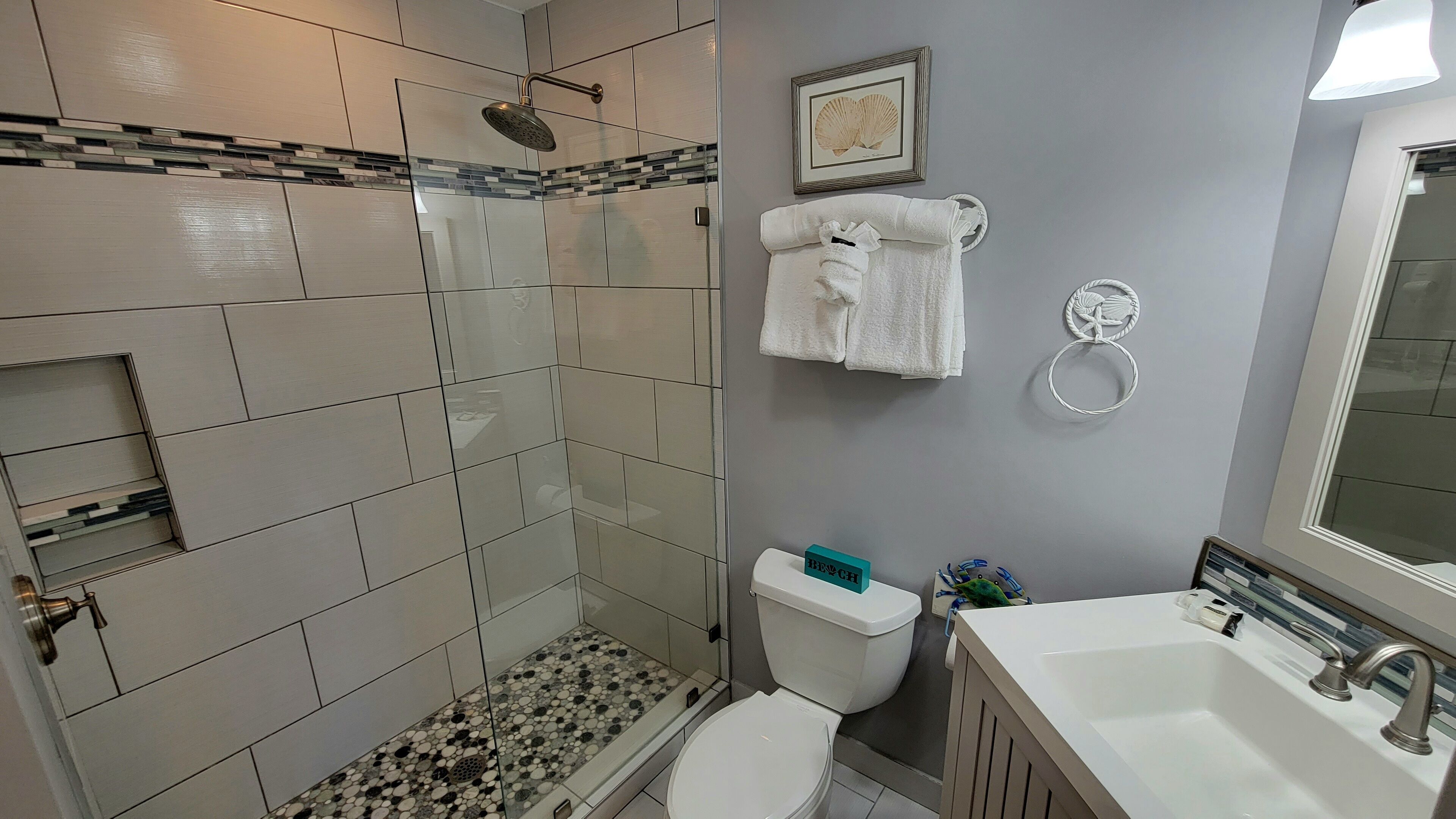 Un baño con ducha, inodoro, lavabo y toallero.