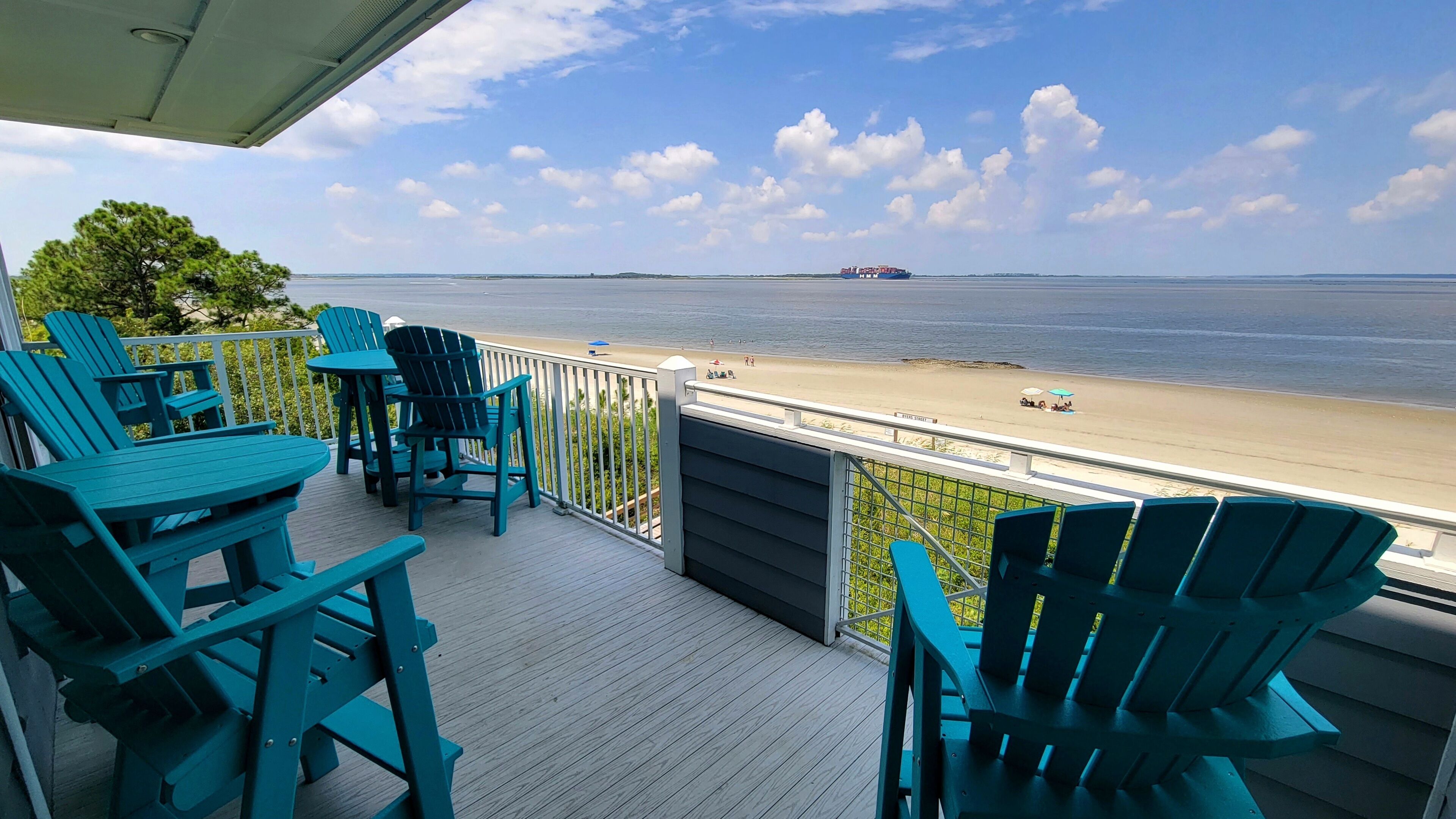 Une terrasse avec des chaises et des tables donnant sur une plage.
