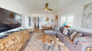 A spacious living room with a large flat-screen TV, a wooden coffee table, and a grey sectional sofa. - Bay View Villas 3 by Tybee Vacation Rentals (Tybee Island)