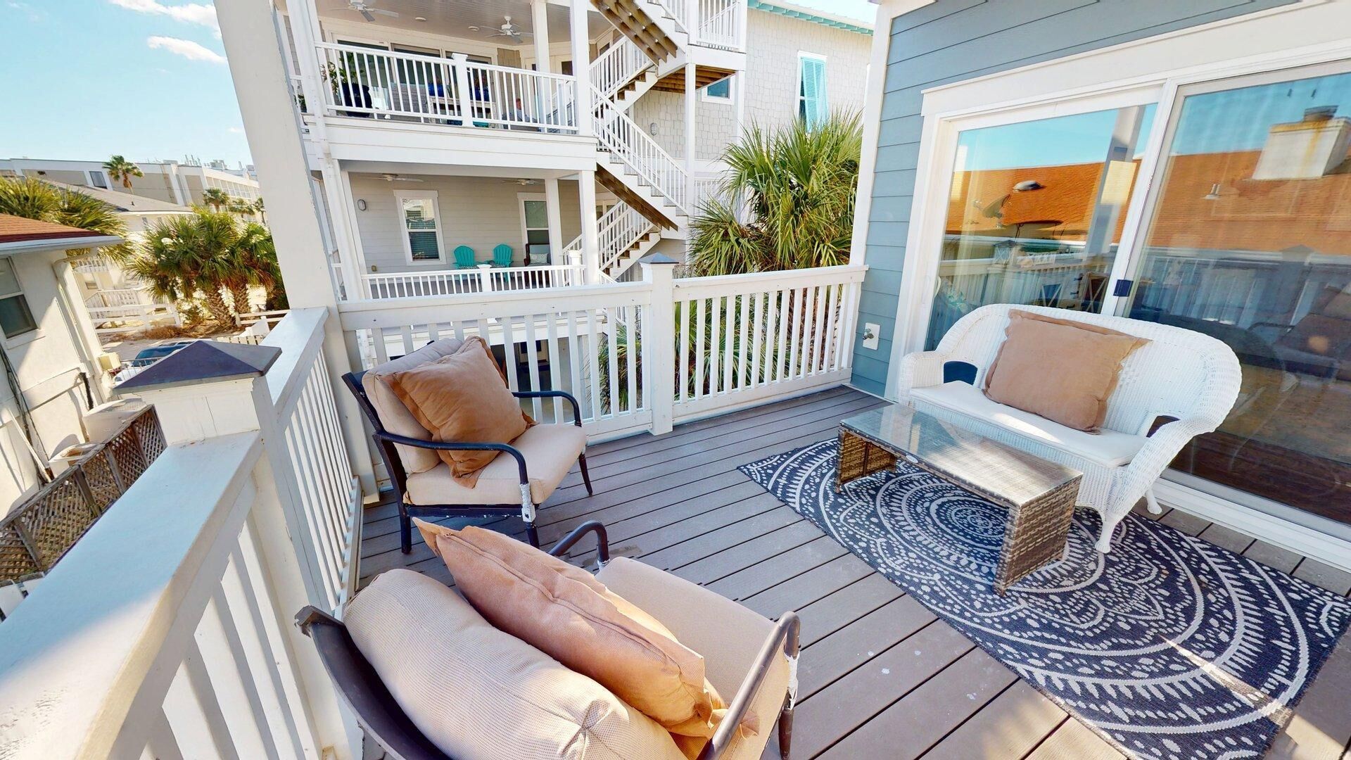 Un balcone con mobili da esterno, tra cui un divano e delle poltrone, e un tappeto decorativo.