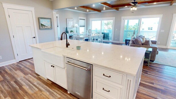 A spacious kitchen with a large island, wooden flooring, and a view to a patio area. - Beach Ya To It Tybee Vacation Rentals (Tybee Island)