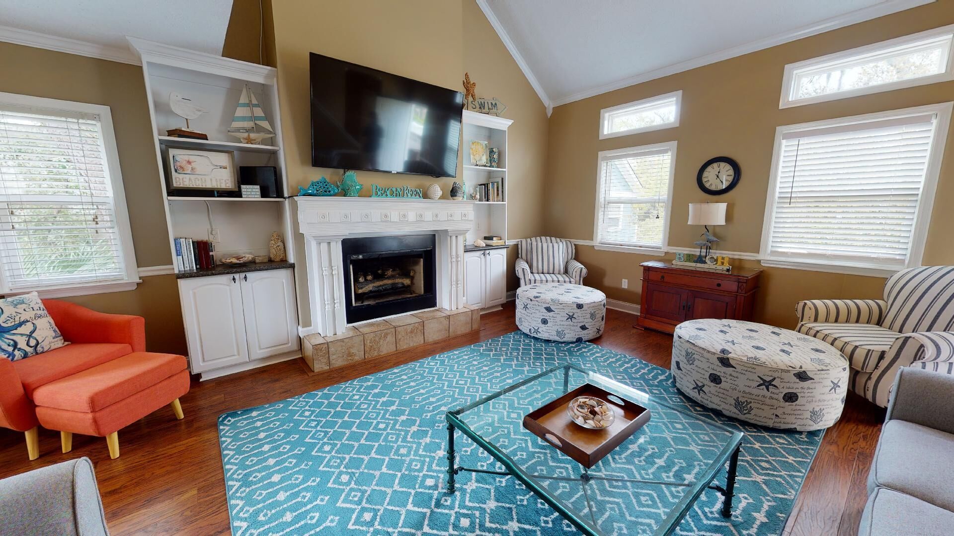 A living room with a fireplace, striped armchairs, a sofa, and a television.