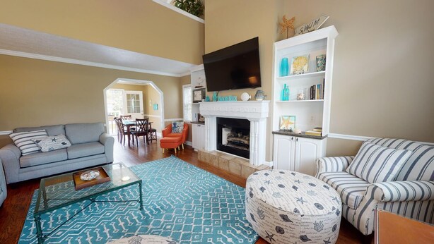 A living room with a fireplace, a television, and a bookshelf. - Beachy Keen Tybee Vacation Rentals (Tybee Island)