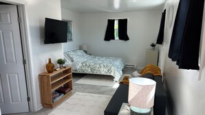 Habitació compacta amb un llit, una taula de nit, una làmpada i un televisor fixat a la paret.