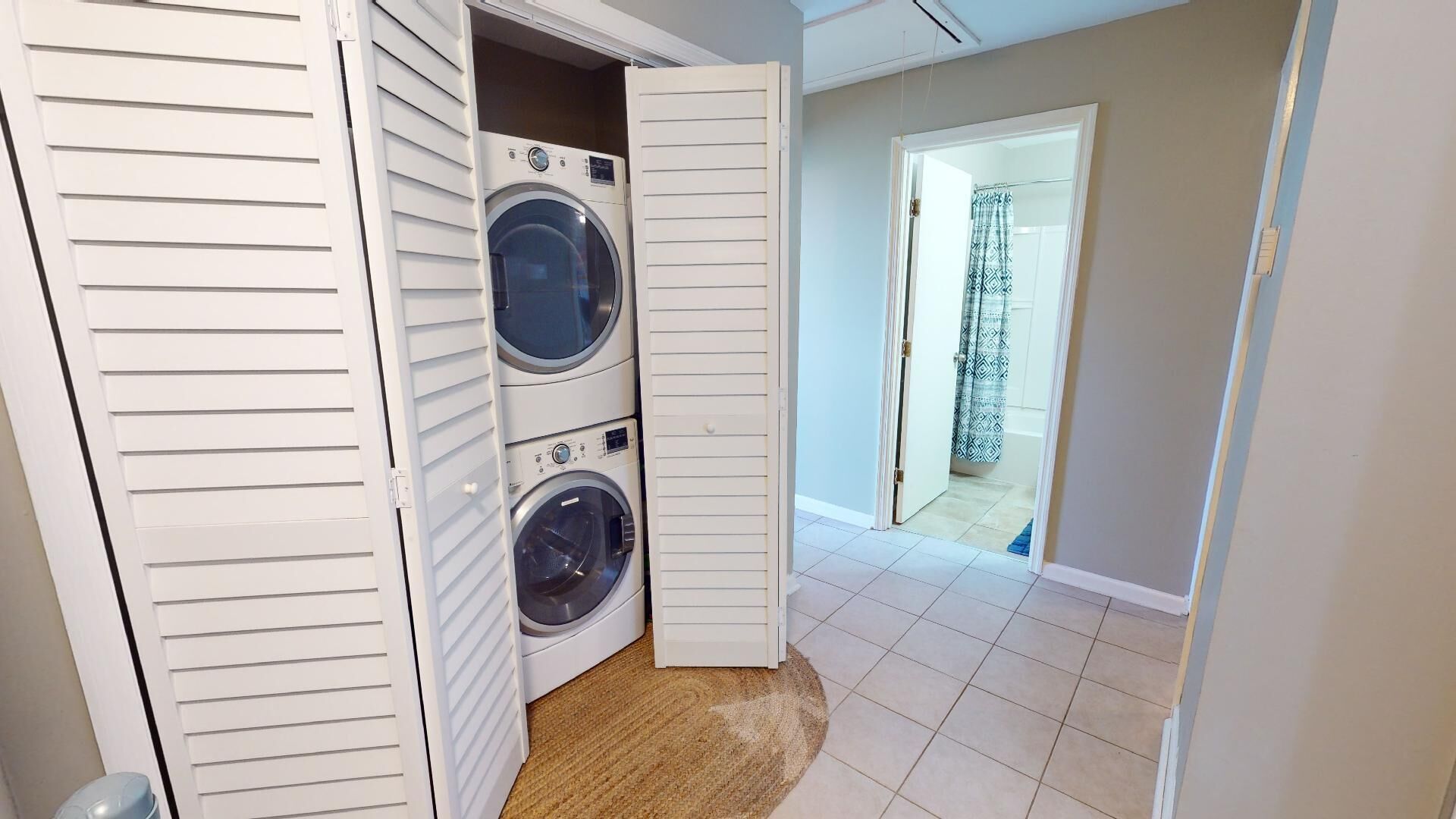 A laundry room with two stacked washers and dryers, a wooden door, and a tiled floor.