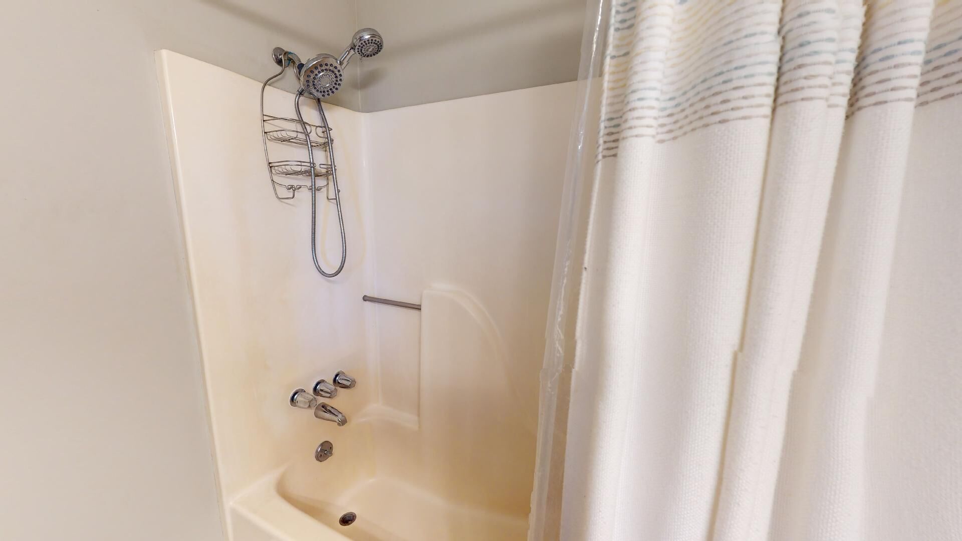 A corner bathroom with a bathtub, shower, and a towel rack.