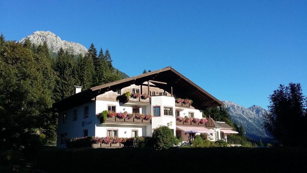 A two-story building with balconies, surrounded by trees and mountains.