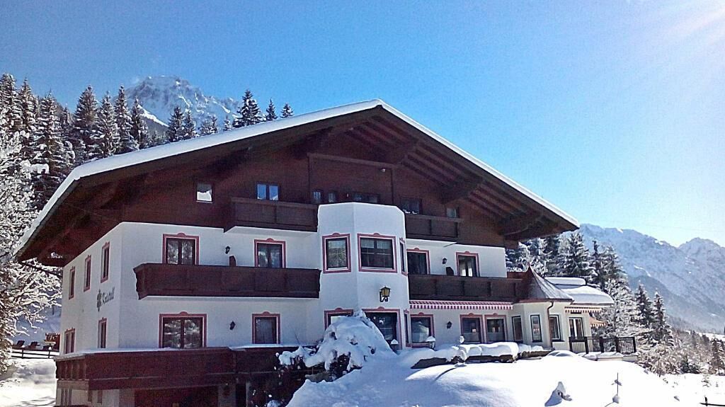 A multi-story hotel with a sloped roof, large windows, and a snow-covered landscape.