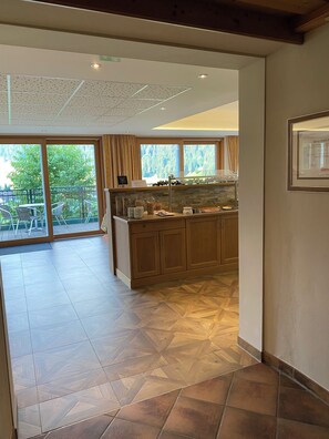 A spacious kitchen with wooden cabinets, a large window, and a view of greenery outside. - Hotel Kristall (Kleinarl)