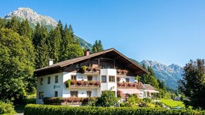 A two-story building with balconies, surrounded by greenery and mountains. - Hotel Kristall (Kleinarl)