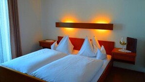 A hotel room with a double bed, two bedside tables, a nightstand, and a wall-mounted light fixture. - Hotel Kristall (Kleinarl)
