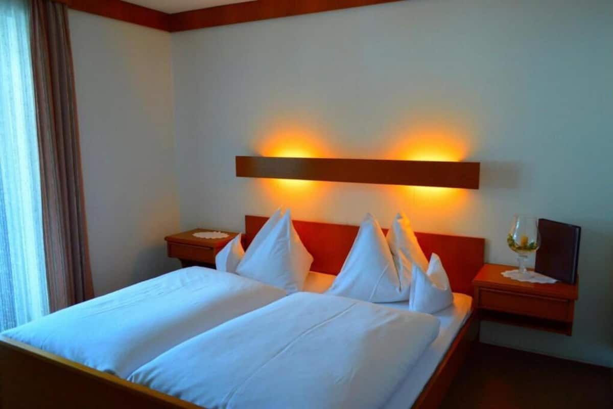 Ein Hotelzimmer mit Doppelbett, zwei Nachttischen, einem Beistelltisch und einer Wandleuchte.