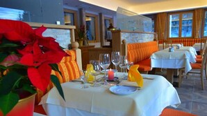 A dining area with tables set for a meal, featuring a candle centerpiece and a potted plant. - Hotel Kristall (Kleinarl)