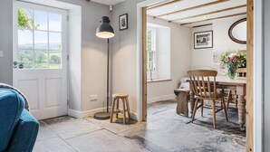 Une pièce dotée d’une grande fenêtre, d’un bureau avec des chaises, d’un lampadaire et d’un plancher en bois.