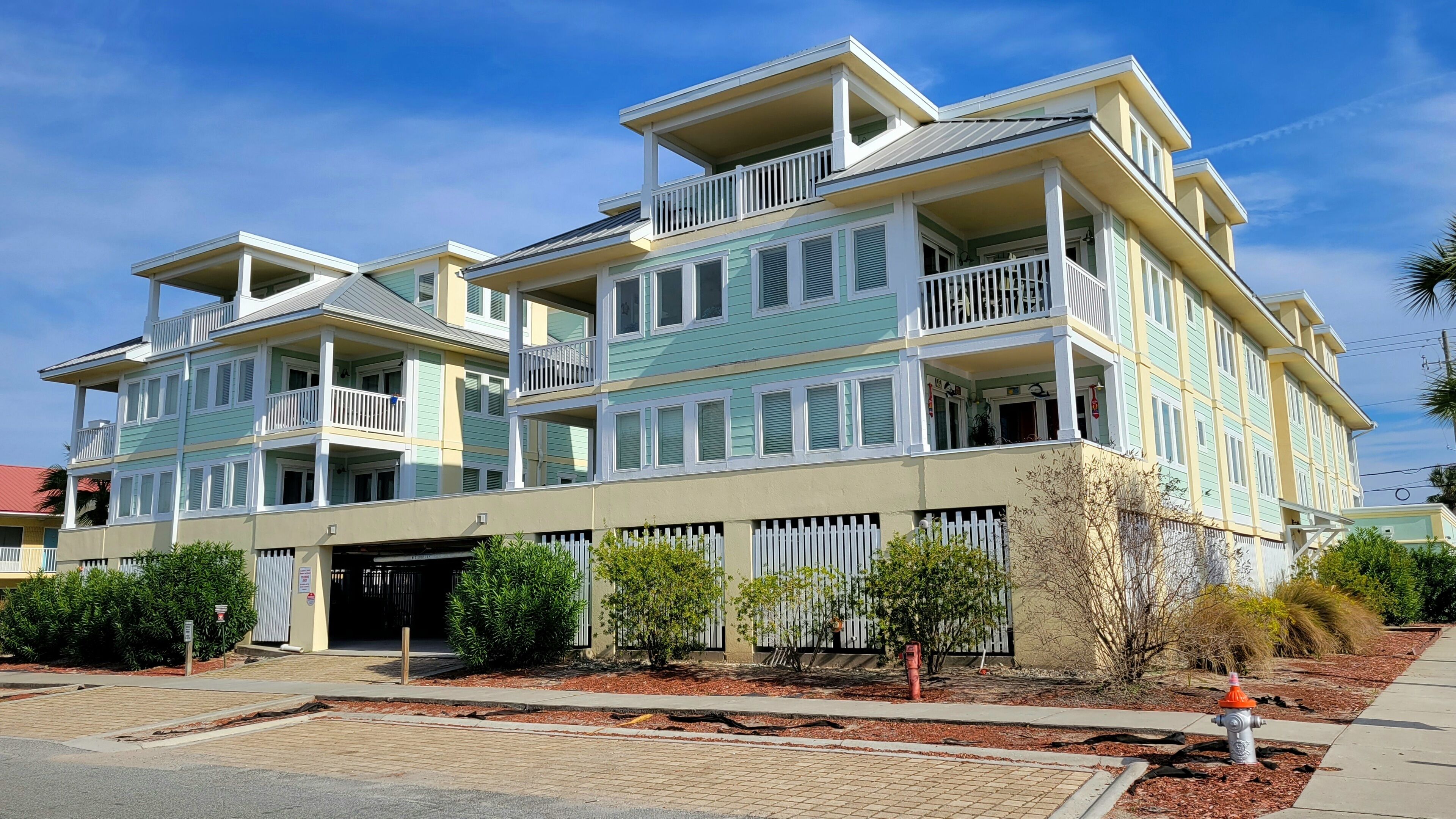 A multi-story residential building with balconies, a gated entrance, and a fire hydrant on the sidewalk.