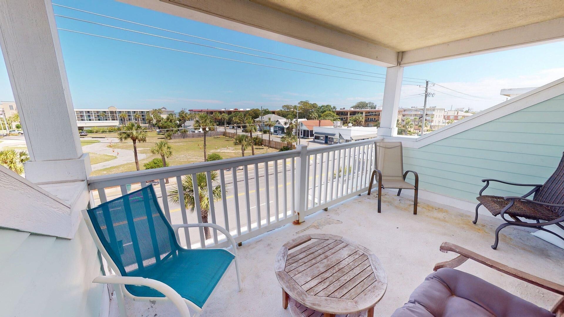 A balcony with a view of a street, a small round table, and two chairs.