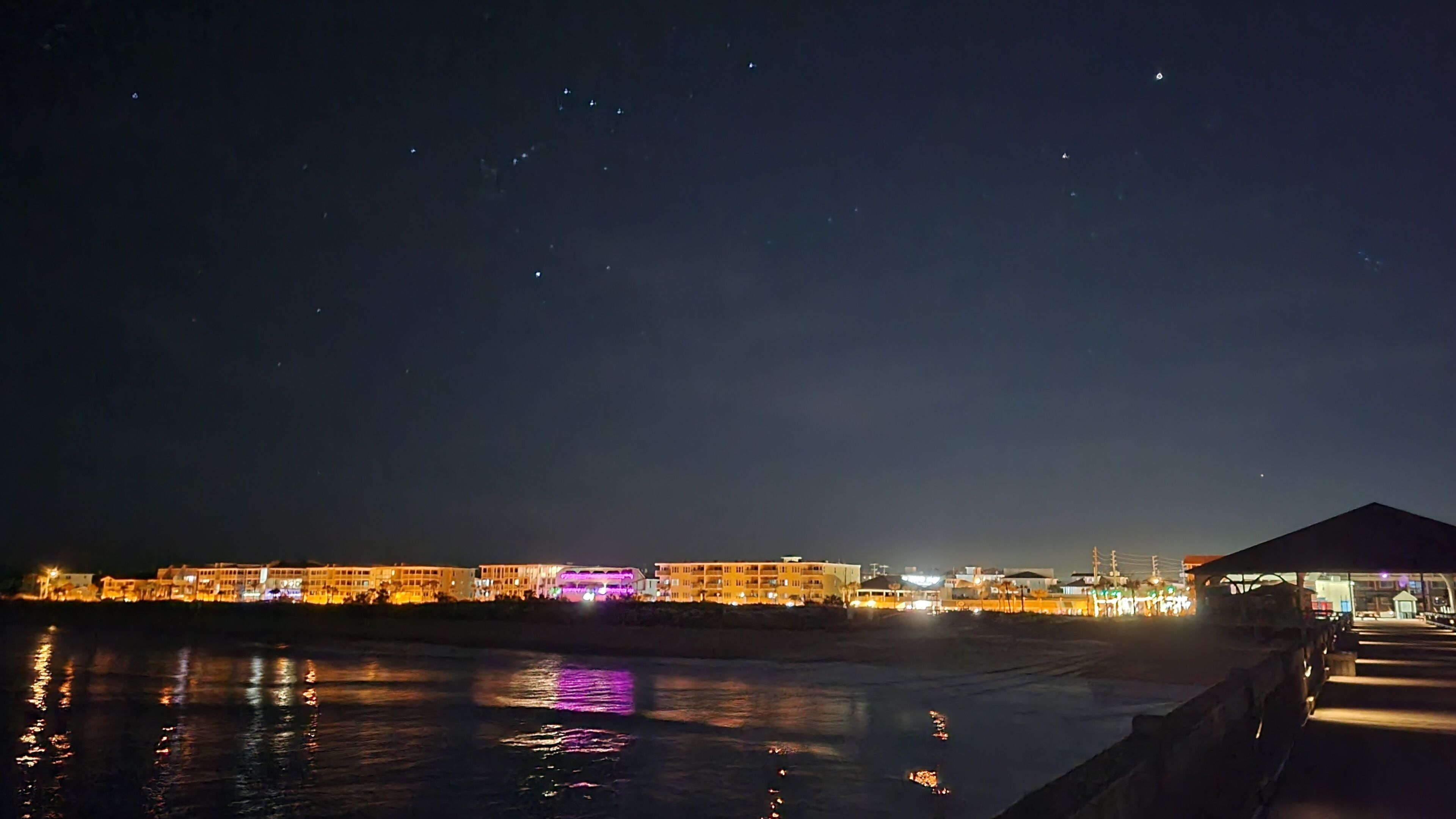 A waterfront hotel with illuminated buildings and a reflective water surface.