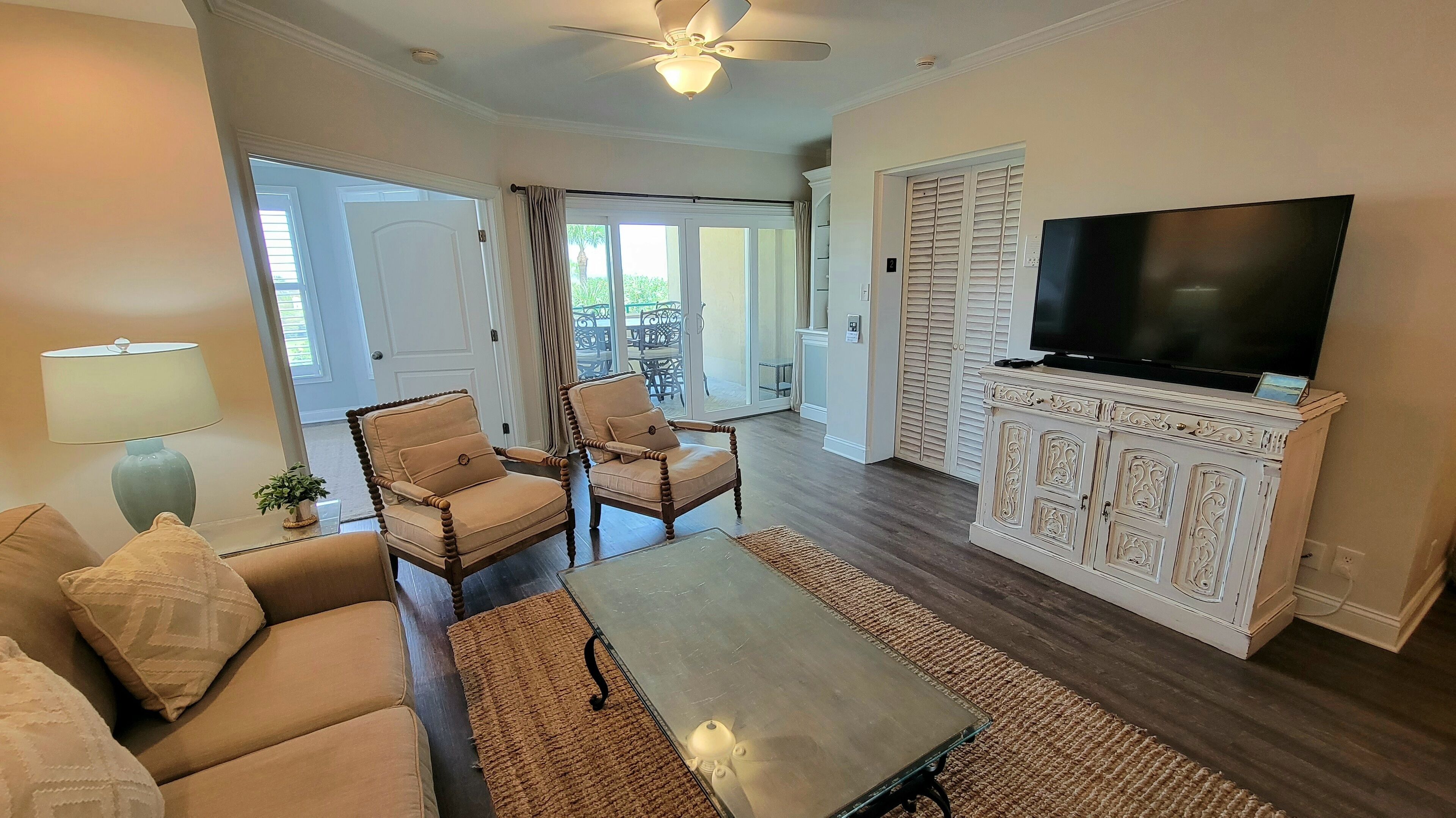 A living room with a sofa, two armchairs, a coffee table, a TV, and a cabinet.