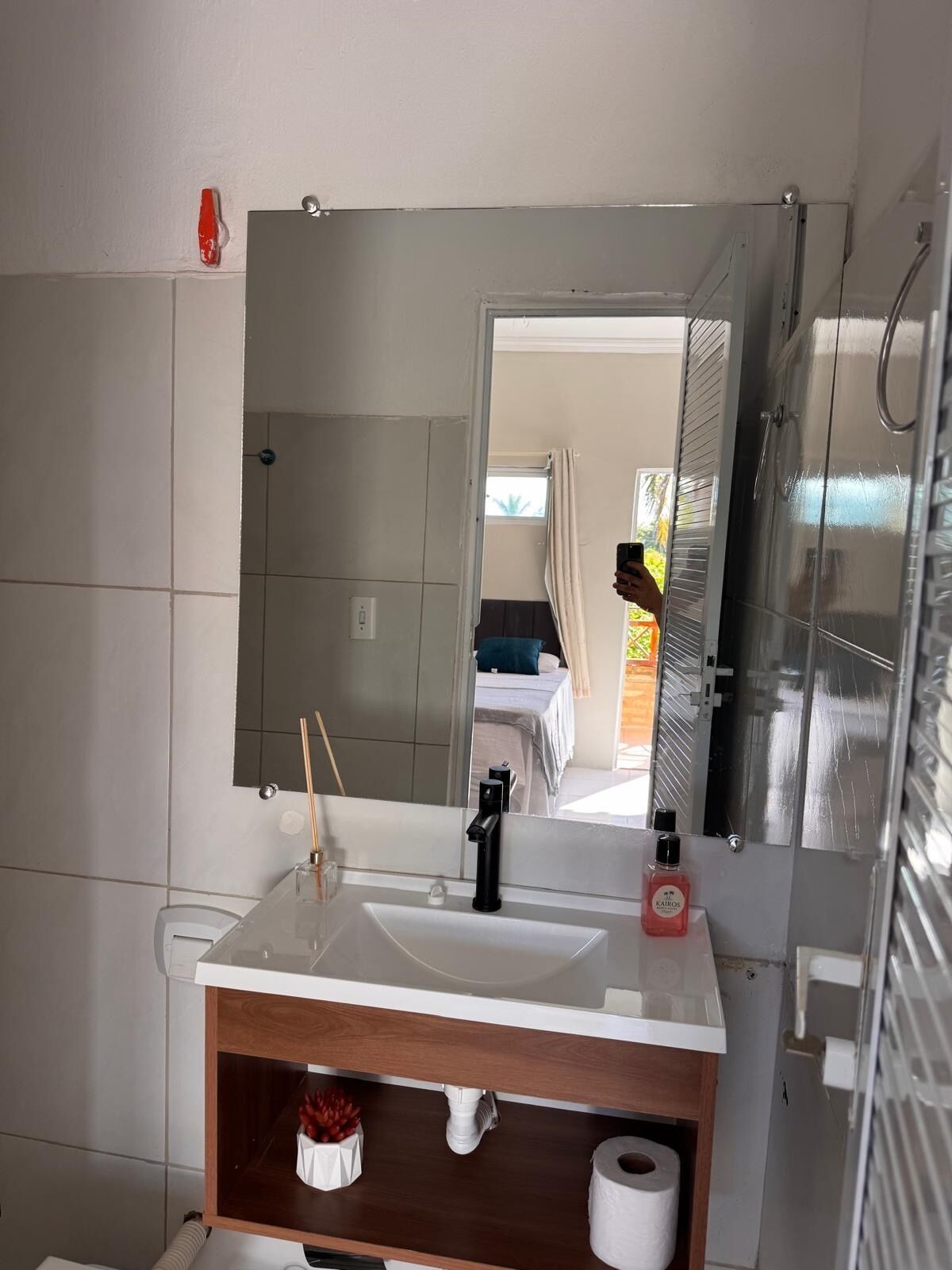 Casa de banho com lavatório branco, espelho e zona de duche.