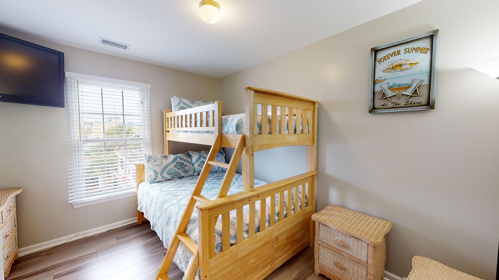 A bunk bed room with a window, a small table, and a wall-mounted TV.