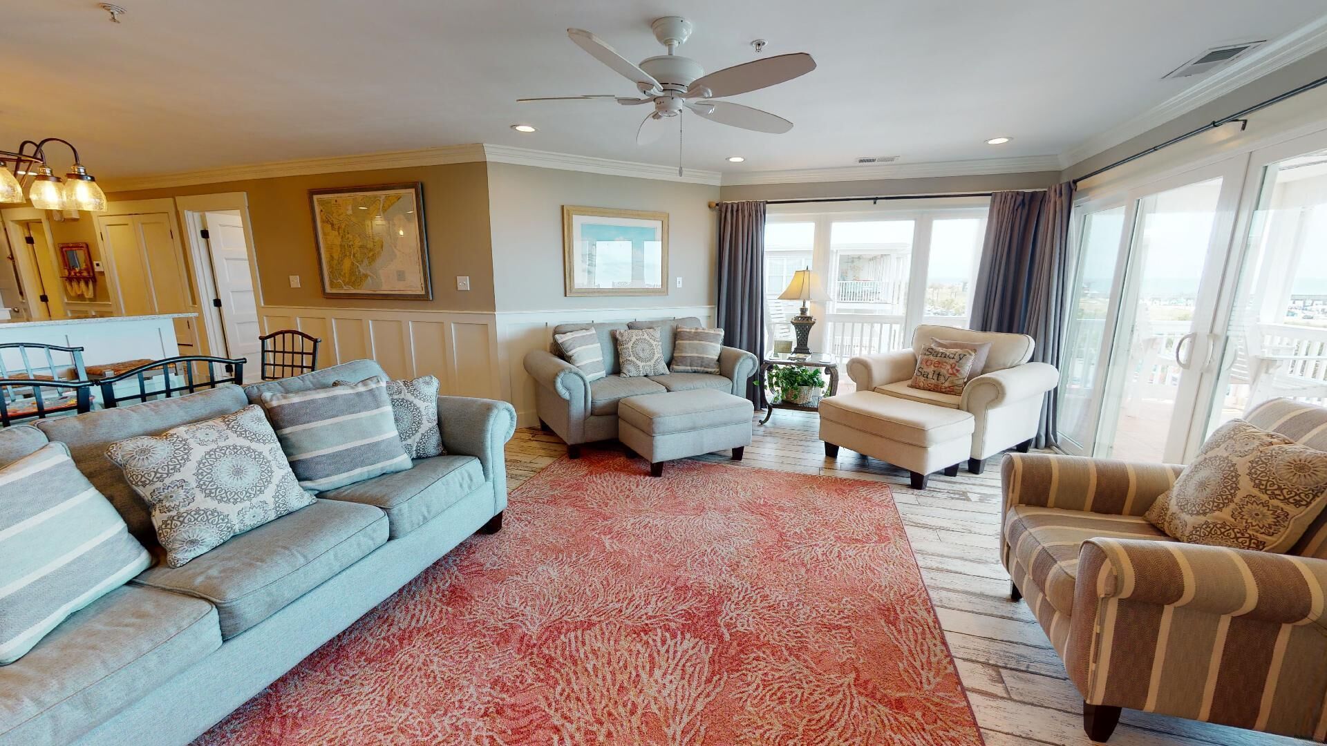 A spacious living room with a grey sofa, a beige armchair, and a patterned rug.