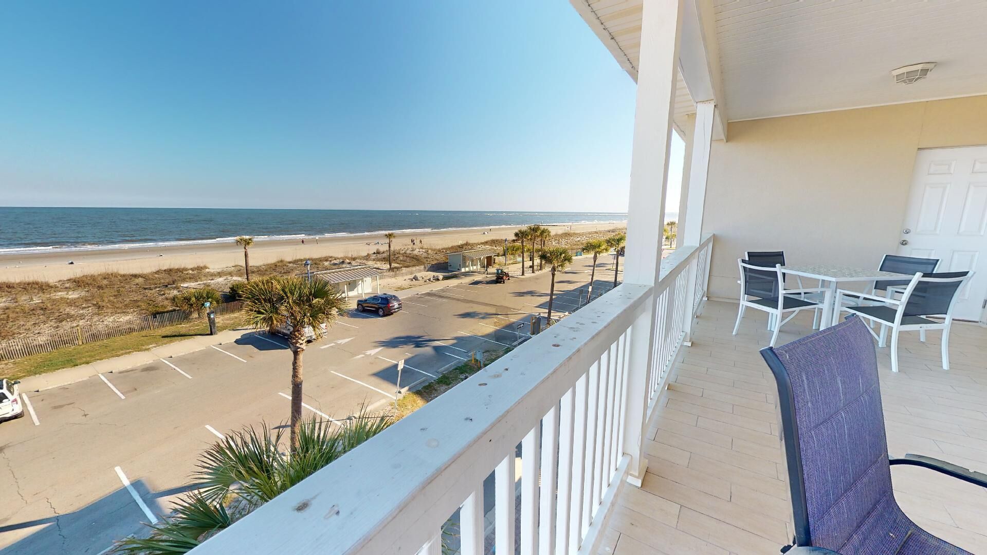 A balcony with a view of a beach and parking lot.