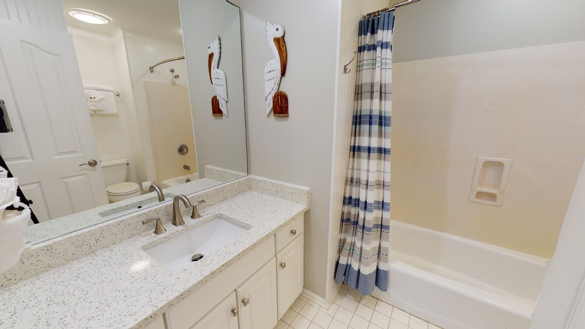 A bathroom with a white sink, two faucets, a mirror, and a shower curtain.