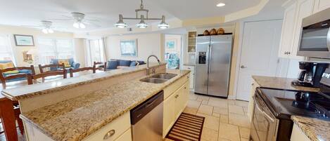 A modern kitchen with granite countertops, stainless steel appliances, and a central island with a sink.